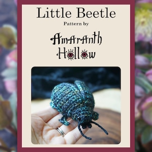 May include: A handmade crocheted beetle in teal, blue, and black, with fine antennae and legs. The image is framed by a burgundy border and features the text "Little Beetle" and "Pattern by Amaranth Hollow".