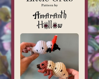 Op de afbeelding: De afbeelding toont twee gehaakte larvenfiguren. Eén is wit met zwarte stippen en rode en zwarte accenten, de andere is bruin en bruin. De tekst "Little Grub" en "Pattern by Amaranth Hollow" staat erboven.
