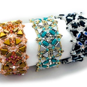 May include: Three beaded bracelets with geometric patterns. The bracelets are made with gold, silver, and black beads. The bracelets are on a white surface.