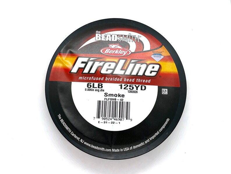 May include: A spool of black FireLine microfused braided bead thread in Smoke color. The spool is labeled with 6LB, 125YD, 0.006in avg.dia, and FLFSH6-42. The spool is made in the USA of domestic and imported components.