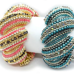 May include: Two beaded bracelets, one in pink, gold, and black, and the other in teal, silver, and black. The bracelets are made of small beads and are twisted into a spiral shape.
