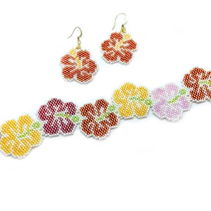 May include: A beaded bracelet and earrings set featuring a floral design. The bracelet has five hibiscus flowers in shades of yellow, pink, red, and orange. The earrings are a matching pair of hibiscus flowers in orange.