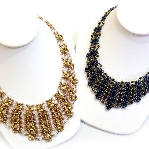 Puede incluir: Dos collares de cuentas, uno dorado y otro azul oscuro, en expositores blancos. Ambos collares están hechos de cuentas pequeñas y tienen un diseño en cascada.