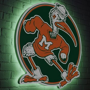 May include: A neon sign featuring the University of Miami Hurricanes mascot, a stylized bird in orange and green. The bird is wearing a sweater with an "M" and a sailor hat. The sign is mounted on a dark brick wall with a green glow.