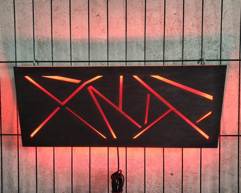 May include: A black wooden wall sconce with a geometric design. The sconce is illuminated with red LED lights.