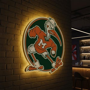 May include: A lighted sign featuring the University of Miami Hurricanes mascot, a stylized pelican in an orange sweater with a large white "M". The sign is set against a brick wall, with a green and orange circular background.