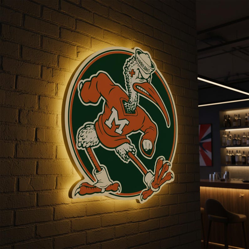 May include: A lighted sign featuring the University of Miami Hurricanes mascot, a stylized pelican in an orange sweater with a large white "M". The sign is set against a brick wall, with a green and orange circular background.