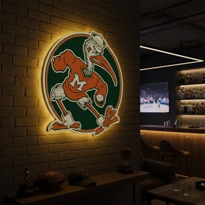 May include: A lighted wall sign featuring a cartoon pelican in an orange jersey with the letter "M" on a green circle. The pelican wears a sailor hat. The sign is mounted on a brick wall.