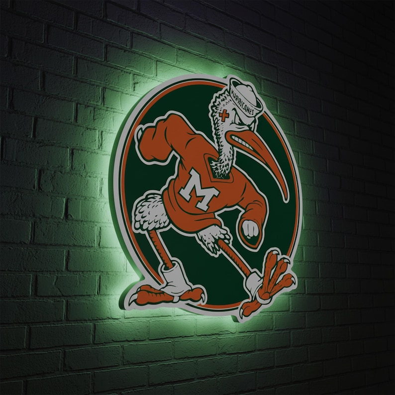 May include: A neon sign featuring the University of Miami Hurricanes mascot, a stylized bird in orange and green. The bird is wearing a sweater with an "M" and a sailor hat. The sign is mounted on a dark brick wall with a green glow.