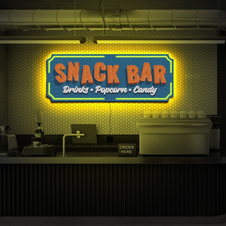 May include: A retro-style snack bar sign with yellow neon lights. The sign reads "Snack Bar" with the words "Drinks, Popcorn, Candy" underneath. The sign is mounted on a wall with a honeycomb pattern.