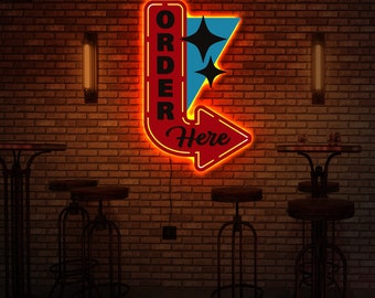 May include: A red and yellow neon sign with the words "Order Here" and a blue star design. The sign is mounted on a brick wall.