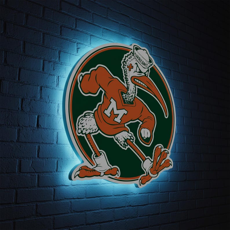 May include: A neon sign featuring the University of Miami Hurricanes mascot, an ibis, in orange and green. The ibis is wearing a sailor hat with the word "Hurricanes" and an orange sweater with a large "M". The sign is mounted on a dark brick wall.