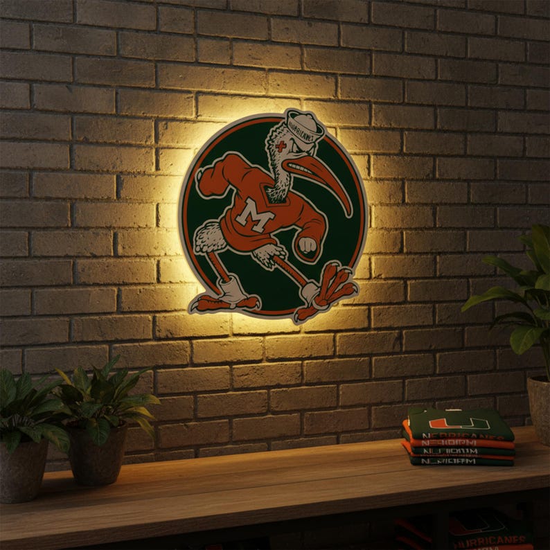 May include: A round, illuminated sign featuring a cartoon pelican in an orange sweater and a sailor hat, with the letter "M" on the sweater. The pelican is set against a green circle. The sign is mounted on a brick wall above a wooden shelf.