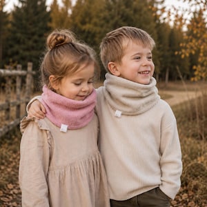 Peut inclure: Un tour de cou en polaire rose et un tour de cou en polaire beige, chacun doté d'une petite étiquette rectangulaire blanche à la base. Ces tours de cou sont doux, texturés et conçus pour s'ajuster confortablement autour du cou.