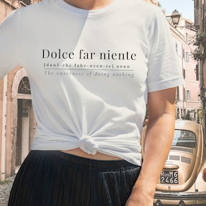 May include: White t-shirt with the text "Dolce far niente" and the definition "[dawl-che fahr-nyen-tel noun The sweetness of doing nothing" printed on the front.