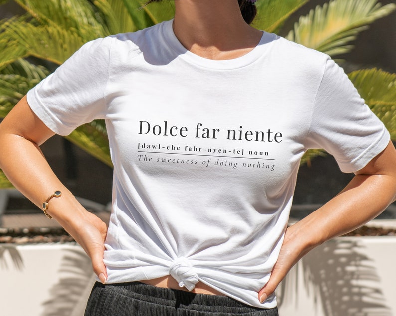 May include: White t-shirt with black text that reads "Dolce far niente" [dawl-che fahr-nyen-tel] noun The sweetness of doing nothing.
