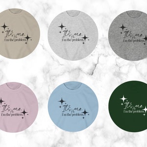May include: Six different color t-shirts with the text "It's me. I'm the problem." printed on them. The text is in black and the shirts are in the colors beige, gray, light pink, light blue, dark green, and light gray.