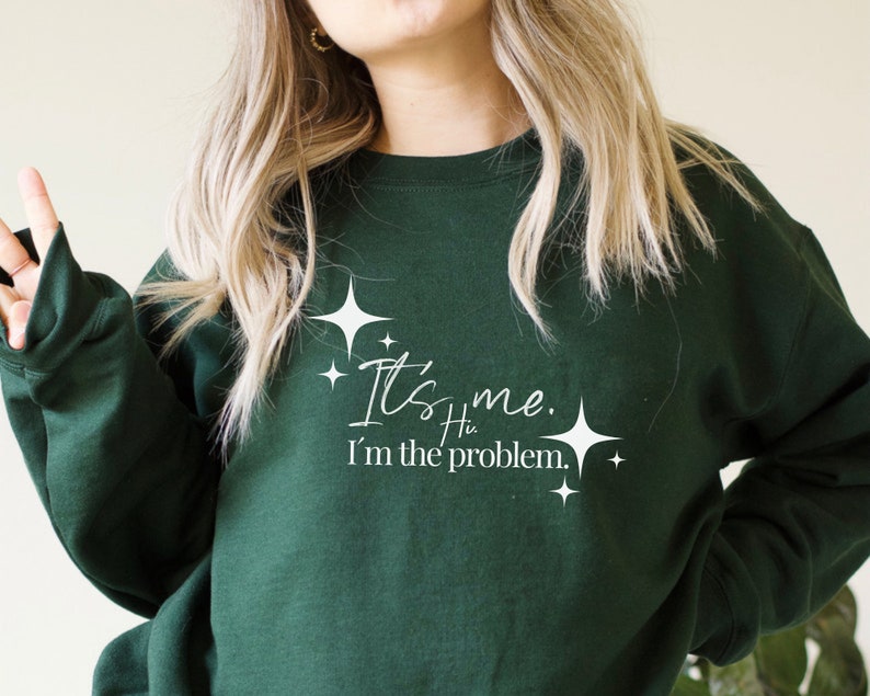 May include: A dark green sweatshirt with white text that reads "It's me. I'm the problem." with small white stars around the text.