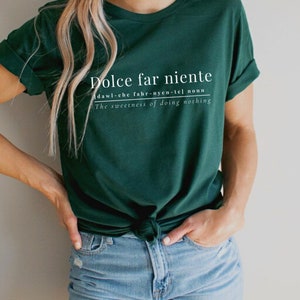 May include: A dark green t-shirt with white text that reads "Dolce far niente" and defines the phrase as "dawl-che fahr-nyen-tel noun The sweetness of doing nothing".