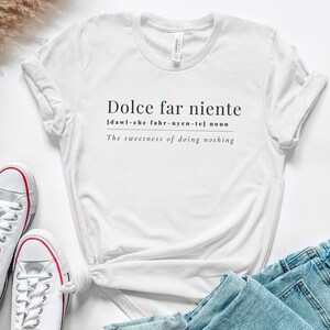 May include: White t-shirt with the text "Dolce far niente" and the definition "[dawl-che fahr-nyen-tel] noun The sweetness of doing nothing".
