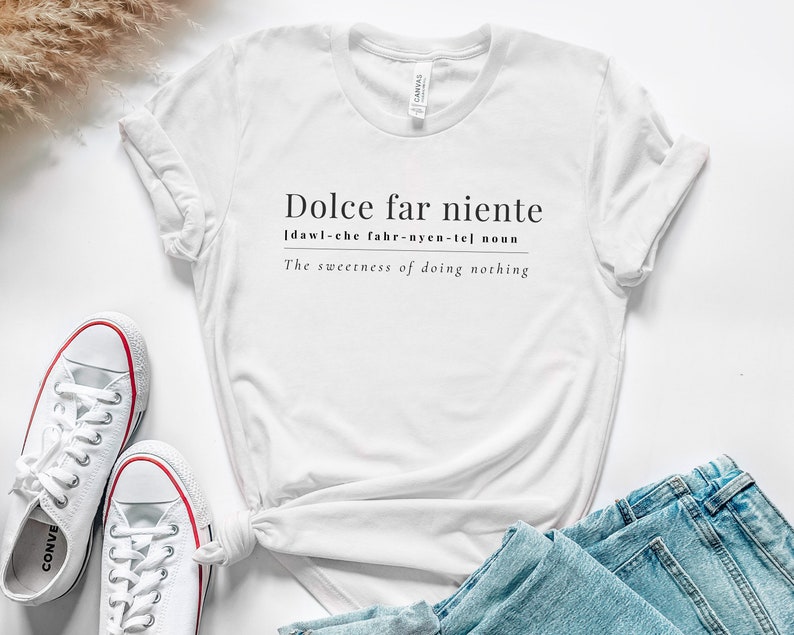 May include: White t-shirt with the text "Dolce far niente" and the definition "[dawl-che fahr-nyen-tel] noun The sweetness of doing nothing".
