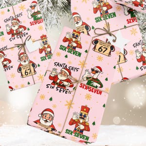 May include: Pink Christmas-themed gift wrap featuring Santa Claus, a goose, and a nutcracker with the text "SANTA SAYS" and "SIX SEVEN". The gifts are tied with twine and adorned with star-shaped tags.