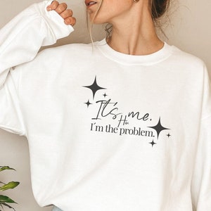 May include: White sweatshirt with a black graphic that says "It's me. I'm the problem." with stars around the text.