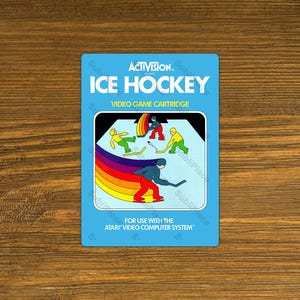 May include: A blue and white Atari video game cartridge for the game Ice Hockey by Activision. The cartridge features a colorful illustration of hockey players on an ice rink.