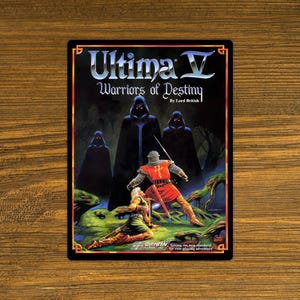 May include: A rectangular sticker featuring the game "Ultima V: Warriors of Destiny." The artwork depicts hooded figures, a knight in red armor, and a fallen figure in a fantasy landscape. The Origin Systems logo is visible.