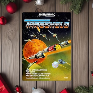 May include: A vintage video game cartridge for the Atari system, titled "Threshold." The cover art features a spaceship, planets, and other space-themed elements. The cartridge is rectangular and has the "TIGERVISION" logo.