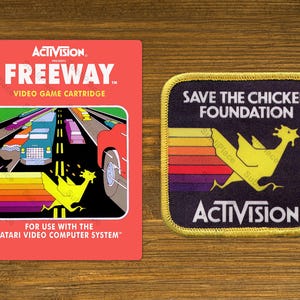 May include: Two retro video game-themed items. One is a red Freeway video game cartridge box with a highway scene and a yellow chicken graphic. The other is a patch with the text "Save the Chicken Foundation" and a yellow chicken graphic.