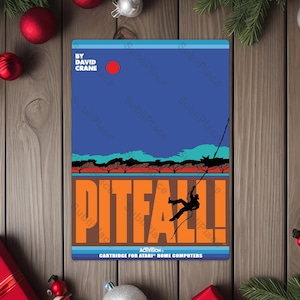May include: A retro video game cartridge for Atari Home Computers. The Pitfall! game cover features a blue sky, orange text, and a silhouetted figure swinging on a vine. The game title is in large orange letters.