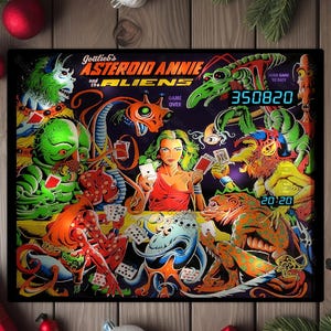 May include: A colorful pinball machine backglass featuring "Asteroid Annie and the Aliens." The artwork depicts a woman in a red dress surrounded by various alien creatures playing cards. The score displays 350820 and 20:20. The game title is at the top.