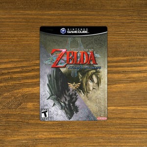 May include: A video game case for The Legend of Zelda: Twilight Princess for the Nintendo GameCube. The case features a dark wolf-like creature and a human character with blonde hair. The game is rated Teen by the ESRB.