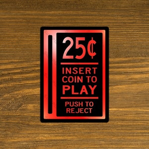 May include: Red and black arcade game coin slot sign with the text "25¢ Insert Coin to Play Push to Reject"