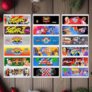 May include: A set of 12 colorful arcade game cabinet stickers featuring various Street Fighter titles, including Street Fighter II, Street Fighter Alpha, and Super Street Fighter II Turbo. The stickers feature iconic characters and logos from the popular fighting game series.