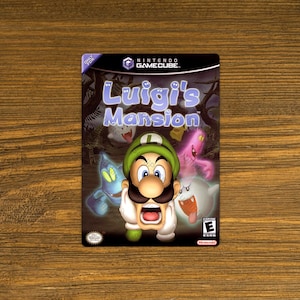 May include: A video game case for the Nintendo GameCube. The case is black with a green, white, and purple image of Luigi from the game Luigi's Mansion. The title of the game is printed in white on the case.