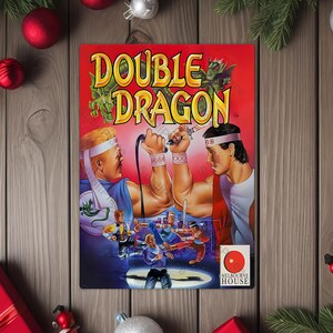 May include: A vintage "Double Dragon" video game box featuring two muscular men in action poses. The box art is predominantly red with the game title in large, yellow letters. The image is surrounded by Christmas decorations.