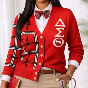 May include: A red V-neck cardigan featuring a plaid pattern on the right side, gold-toned buttons, and white Greek letters on the left chest. The cardigan is worn over a white collared shirt with a matching plaid bow tie and tan trousers.