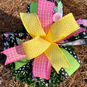 Peut inclure: Une couronne avec un nœud en ruban jaune à pois, ruban vichy rose, ruban vert à pois noirs et ruban floral noir.