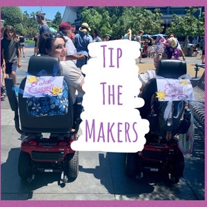 May include: Two people in motorised scooters decorated with "Just Engaged!" signs. The scooters are red and black with white wheels. The text "TIP THE MAKERS" is superimposed on the image.