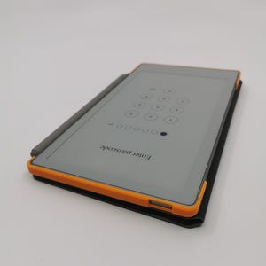 May include: A rectangular tablet with a gray screen displaying a passcode entry screen. The tablet has an orange border and is in a black case. A gray stylus rests on the tablet. The text "Enter passcode" is visible.