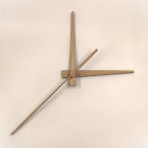 Op de afbeelding: Een set houten wijzers voor een klok, de uurwijzer wijst naar 12 uur en de minutenwijzer wijst naar 3 uur.