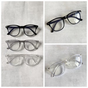 May include: Four pairs of spectacles, two black and two clear, on a white background. The black spectacles have blue tinted lenses. The clear spectacles have clear lenses.