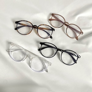 May include: Four pairs of spectacles with different frames and lenses. The frames are black, brown, clear, and tortoiseshell. The lenses are clear.