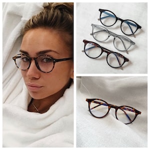May include: A close-up of three pairs of round spectacles with blue light blocking lenses. The spectacles are in tortoise shell, grey, and black frames.