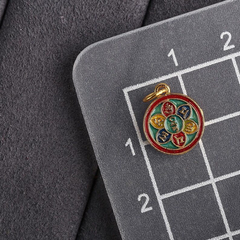 Puede incluir: Un colgante de color dorado con un dise&ntilde;o redondo y multicolor. El colgante presenta un dise&ntilde;o circular con seis secciones, cada una de un color diferente: rojo, verde, amarillo, azul y blanco. El centro del colgante tiene un s&iacute;mbolo dorado.