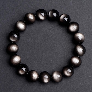 May include: A black gemstone bracelet with a silver sheen. The bracelet is made of round beads and is strung on a stretchy cord.