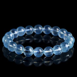 以下が含まれることがあります： 丸いビーズが付いた薄い青色のアクアマリンの宝石のブレスレットです。