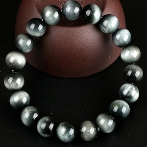 May include: A gray and white gemstone bracelet with round beads. The bracelet is made of natural stones and has a polished finish.